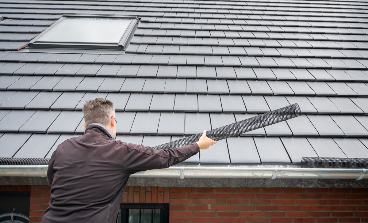 Person installing gutter guard on roof.