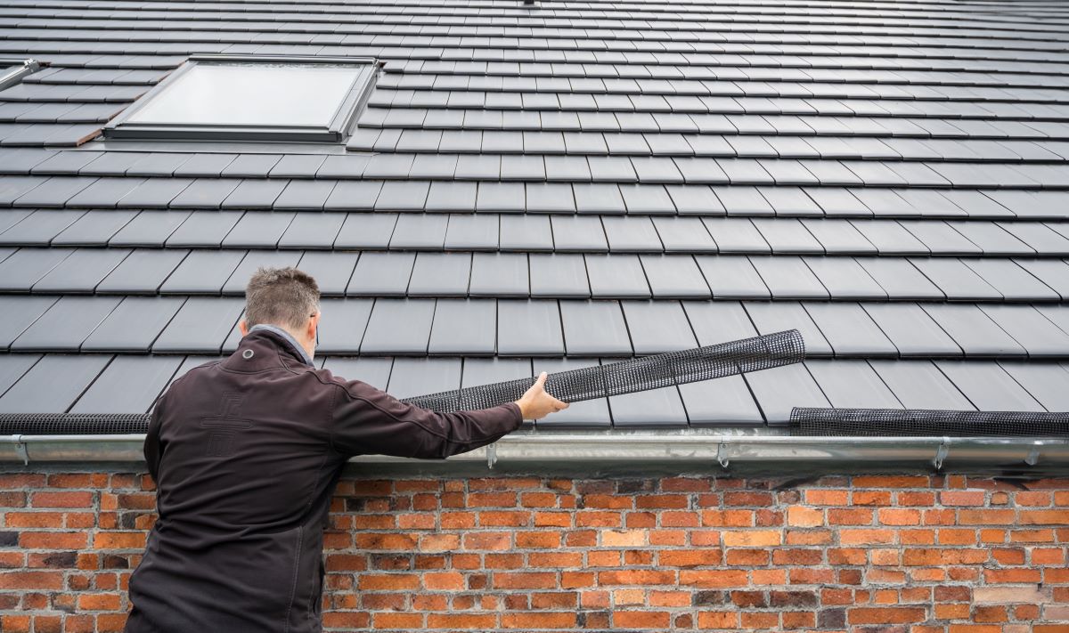 Man installing mesh gutter guard for rain and fire protection in Reno, Nevada
