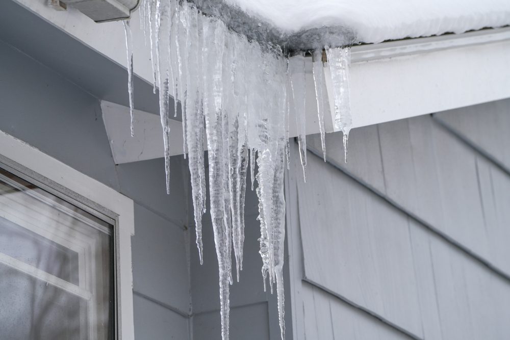 Icicles hanging from house roof in winter.