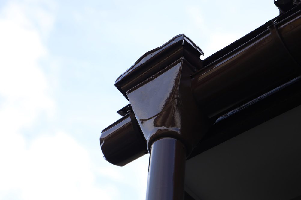Close-up of dark brown roof gutter and downspout