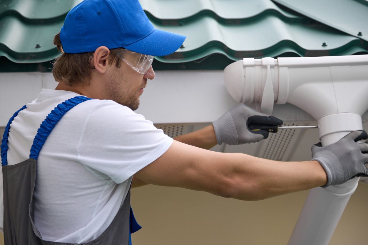 Man repairing gutters on house