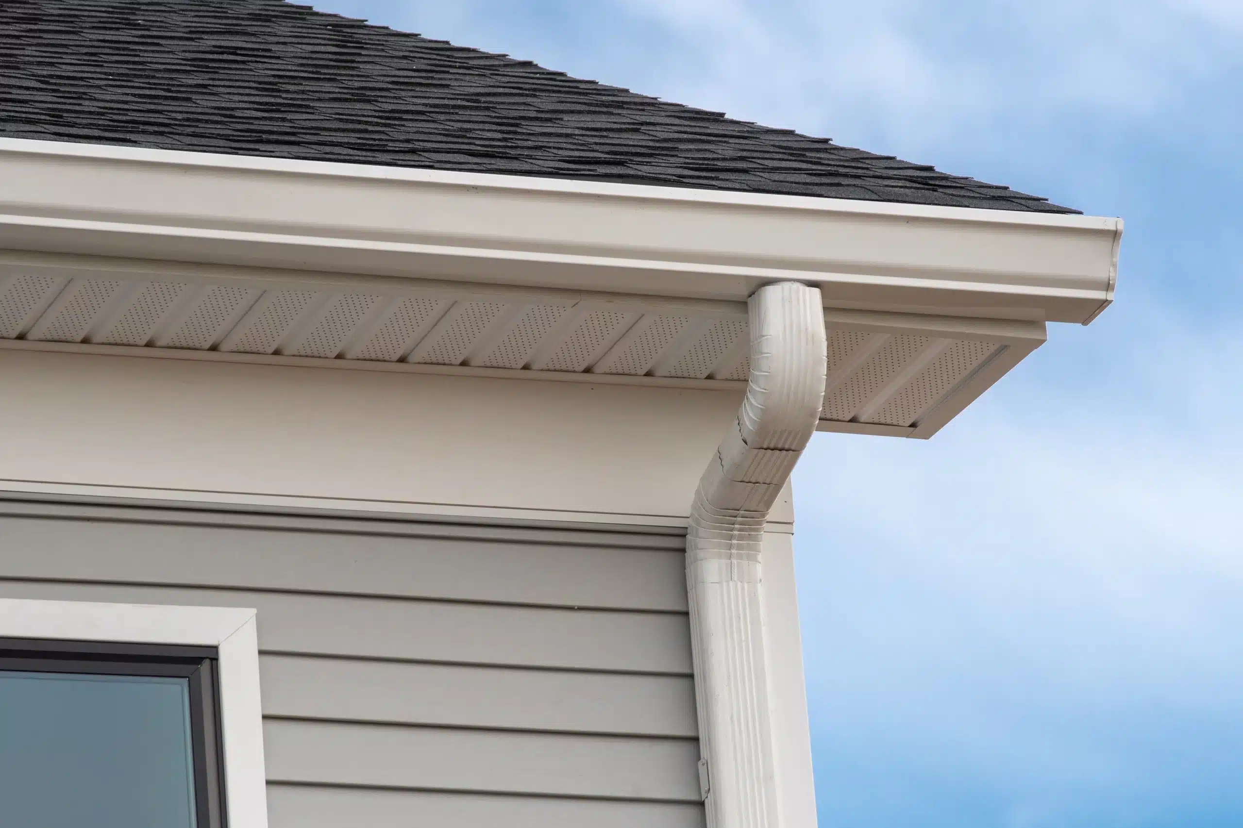 Battle Born Gutters installer fitting a seamless gutter along a metal roof