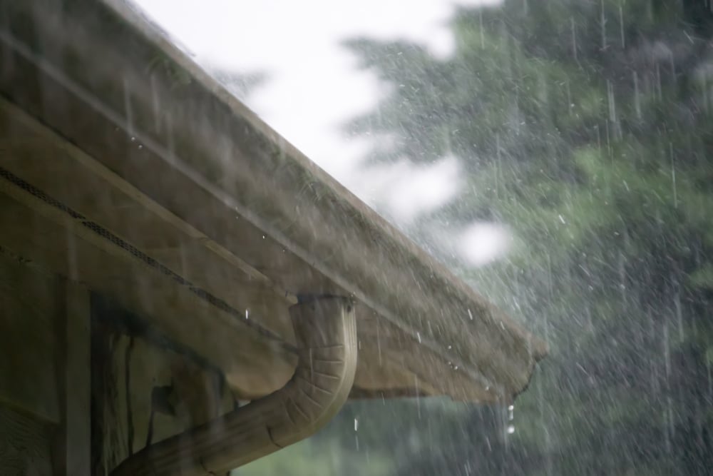 Rainwater spilling over the edge of a gutter during a storm