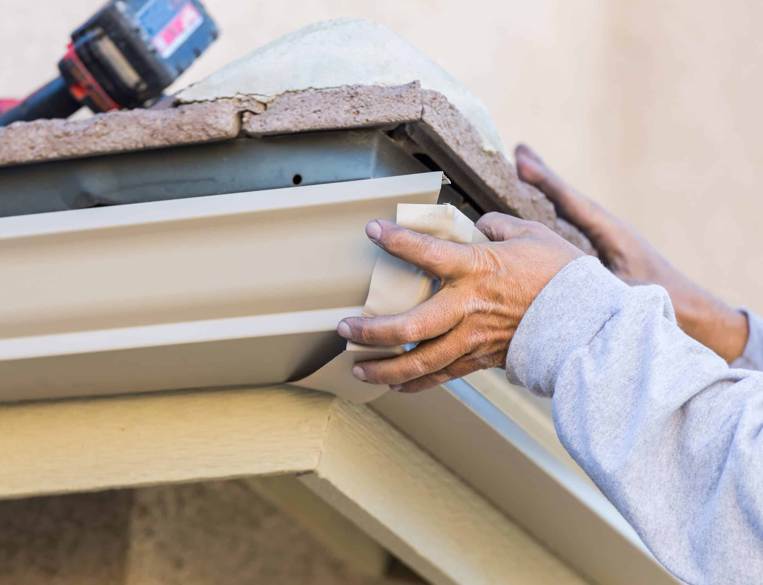Hands fitting a white seamless gutter end cap