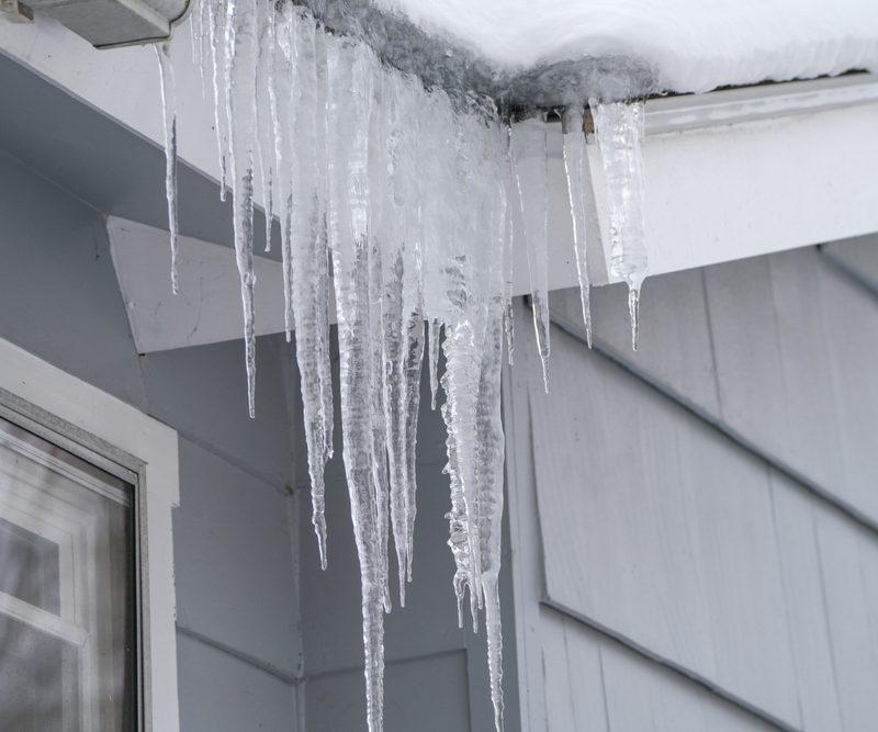 Icicles hanging from house roof in winter.